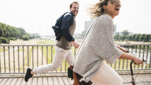 Happy couple crossing a bridge with bicycle and by foot