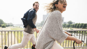 Happy couple crossing a bridge with bicycle and by foot