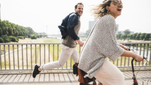 Happy couple crossing a bridge with bicycle and by foot
